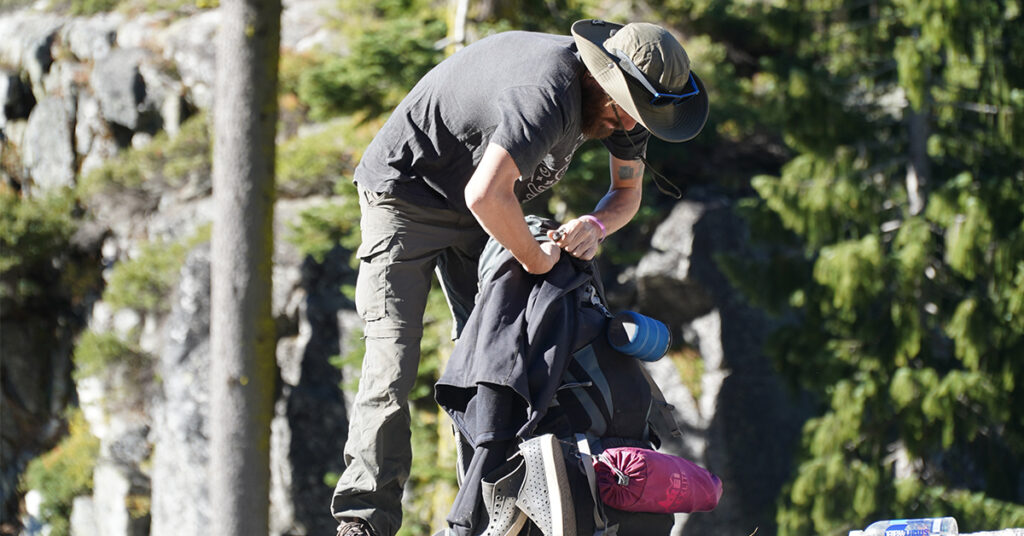 Man Packing Gear into Backpack